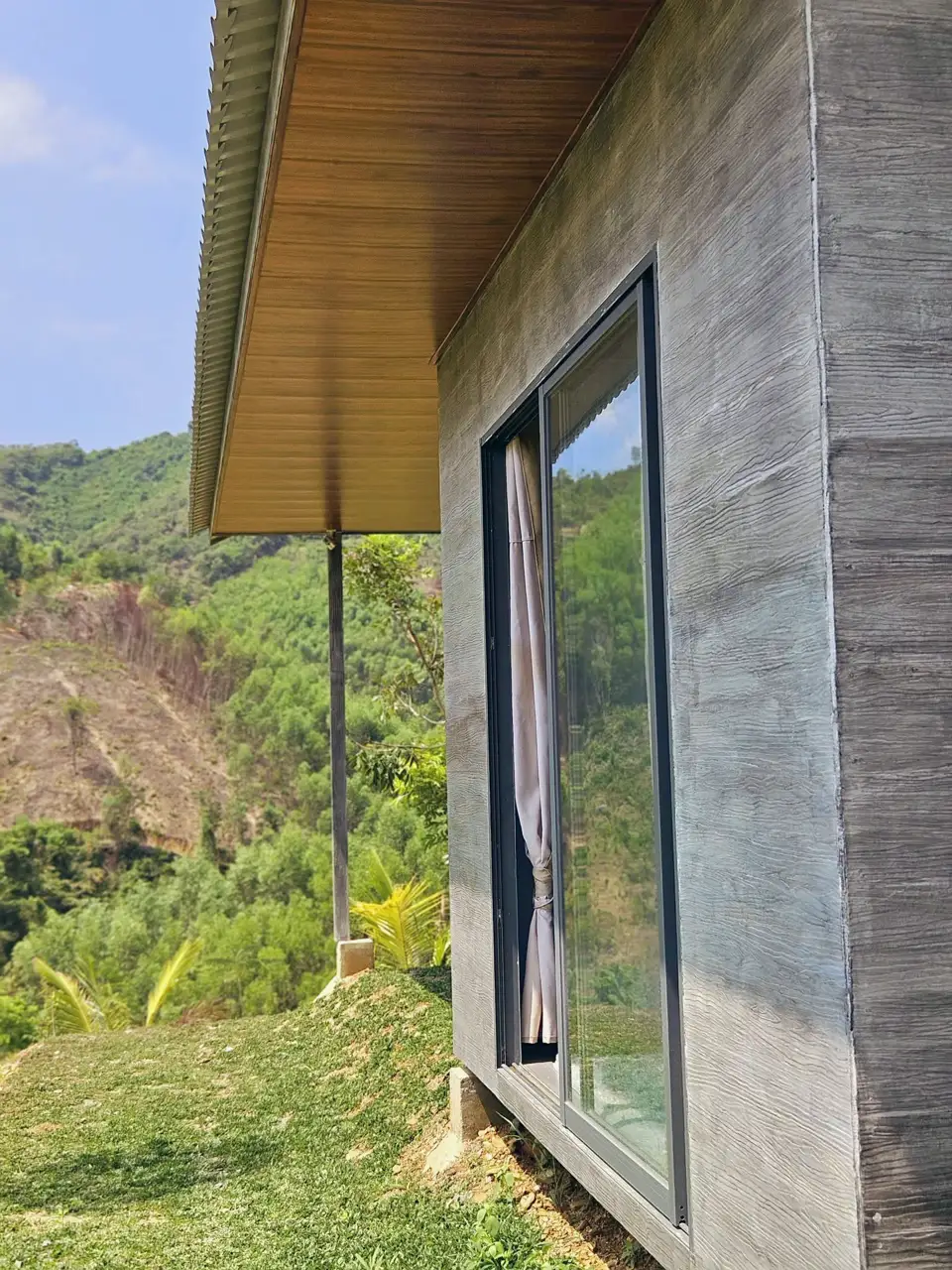Hông bungalow giả gỗ xám, cửa kính trượt, nhìn ra thung lũng
