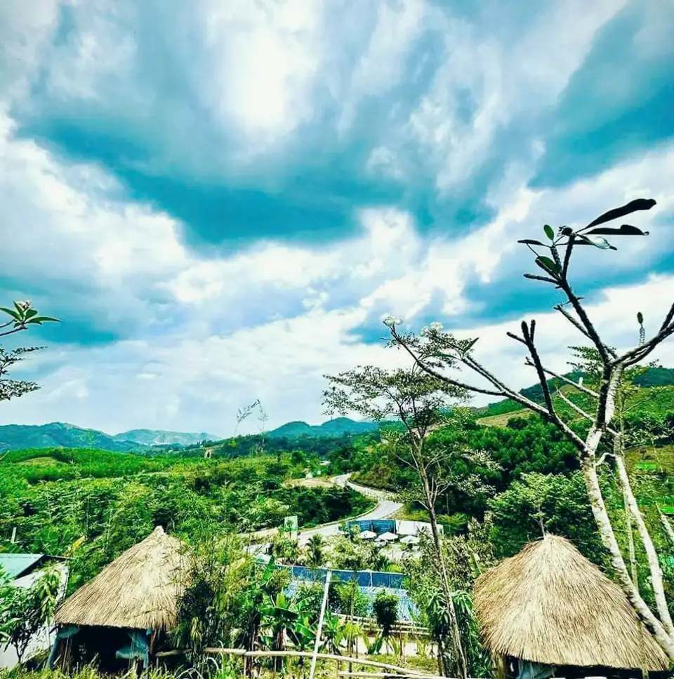 Từ đồi nhìn xuống thung lũng, hai chòi tranh và dãy núi mây thấp
